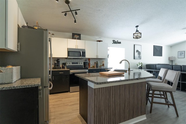11761 Hatcher Cir, Orlando, FL 32824 - kitchen with stainless steel appliances, light wood-style floors, a kitchen breakfast bar, backsplash, and dark stone counters