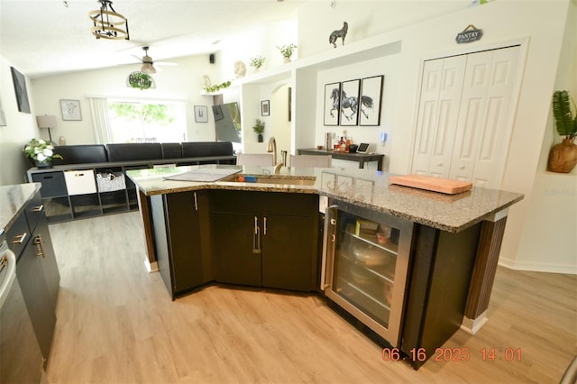 11761 Hatcher Cir, Orlando, FL 32824 - kitchen featuring wine cooler, light wood-style floors, ceiling fan, vaulted ceiling, and a center island with sink