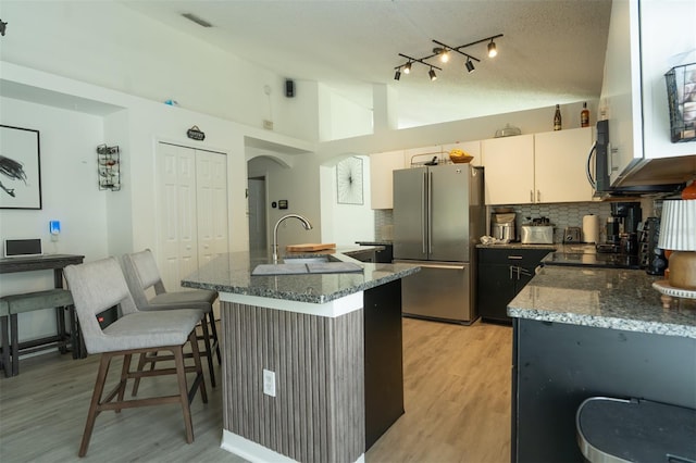 11761 Hatcher Cir, Orlando, FL 32824 - kitchen with stainless steel appliances, decorative backsplash, dark stone counters, light wood-type flooring, and high vaulted ceiling