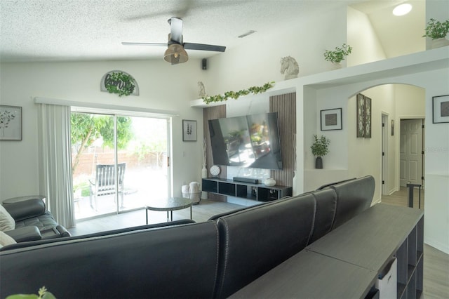 11761 Hatcher Cir, Orlando, FL 32824 - living room featuring wood finished floors, arched walkways, ceiling fan, a textured ceiling, and high vaulted ceiling