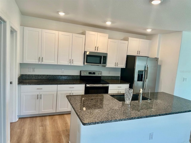 9937 Aqua Miles Path, Wesley Chapel, FL 33545 - kitchen with appliances with stainless steel finishes, white cabinets, light wood-style flooring, recessed lighting, and dark stone countertops