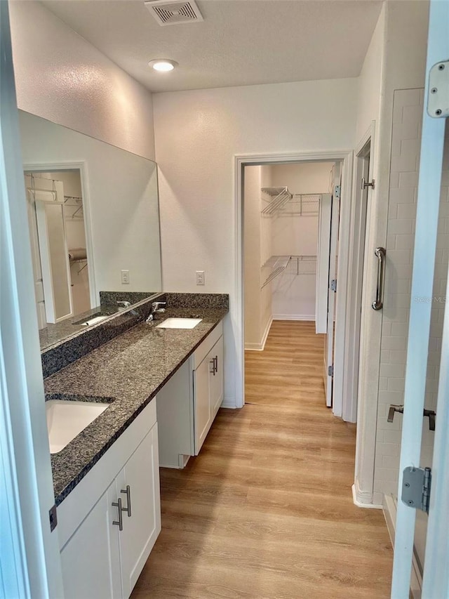 9937 Aqua Miles Path, Wesley Chapel, FL 33545 - full bathroom featuring a walk in closet, wood finished floors, double vanity, and a tile shower