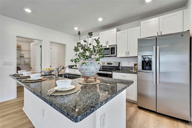 9937 Aqua Miles Path, Wesley Chapel, FL 33545 - kitchen featuring stainless steel appliances, white cabinets, light wood-style floors, a kitchen island with sink, and recessed lighting