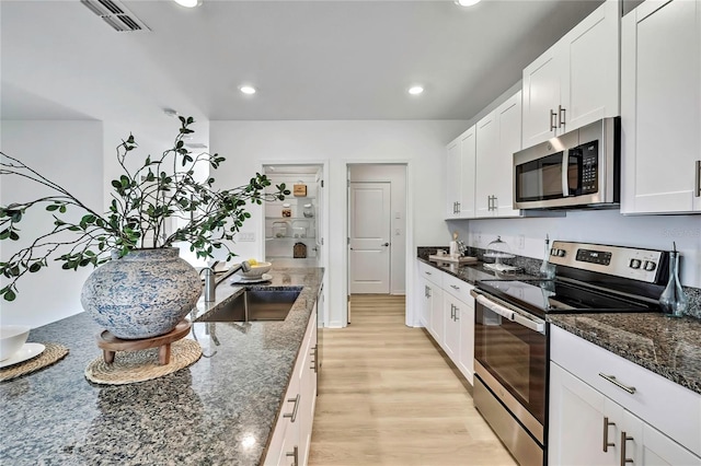 9937 Aqua Miles Path, Wesley Chapel, FL 33545 - kitchen featuring appliances with stainless steel finishes, recessed lighting, white cabinets, light wood finished floors, and dark stone counters