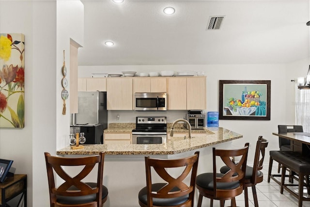 1716 Westerly Dr, Brandon, FL 33511 - kitchen featuring stainless steel appliances, light brown cabinets, a kitchen breakfast bar, light stone countertops, and a peninsula