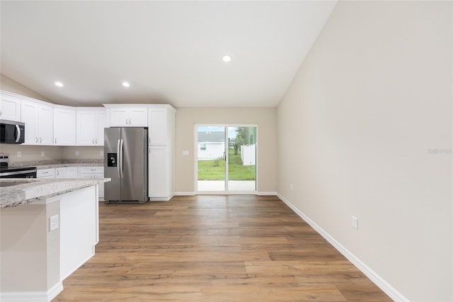 1059 NE 130th Ter, Silver Springs, FL 34488 - kitchen featuring stainless steel appliances, lofted ceiling, white cabinets, light stone counters, and light wood-style flooring