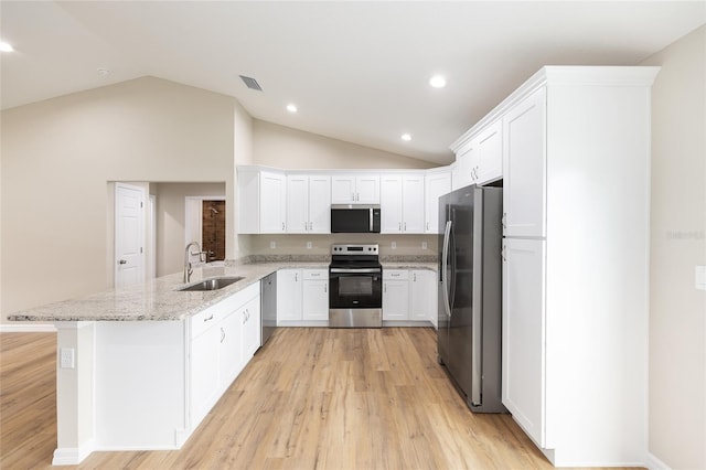 1059 NE 130th Ter, Silver Springs, FL 34488 - kitchen with appliances with stainless steel finishes, a peninsula, vaulted ceiling, white cabinets, and light wood-style floors