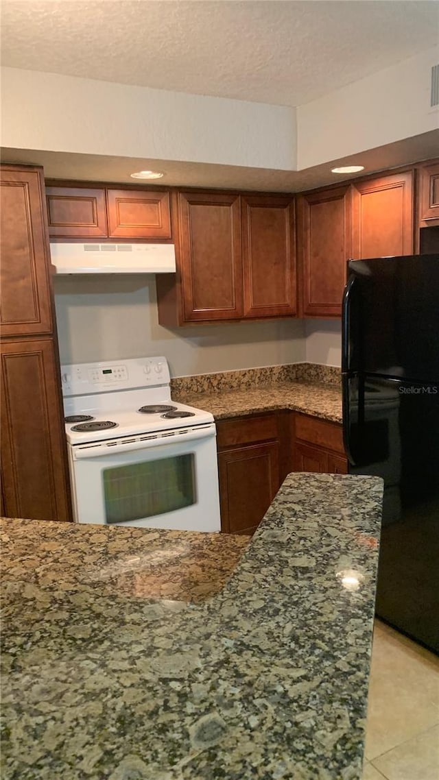 5725 Gatlin Ave Unit 315, Orlando, FL 32822 - kitchen featuring white electric range oven, freestanding refrigerator, under cabinet range hood, dark stone countertops, and a textured ceiling