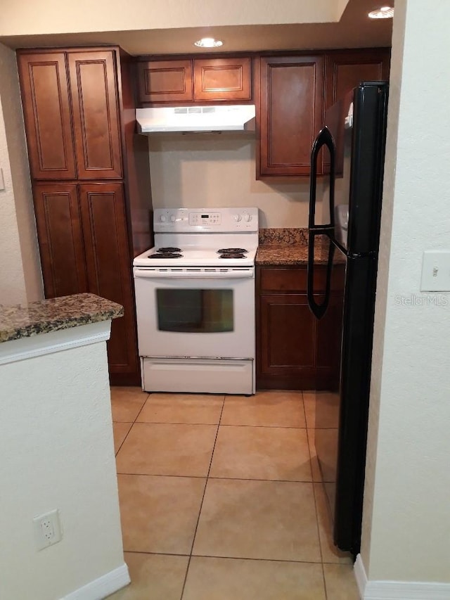 5725 Gatlin Ave Unit 315, Orlando, FL 32822 - kitchen with white range with electric stovetop, under cabinet range hood, freestanding refrigerator, dark stone counters, and light tile patterned flooring