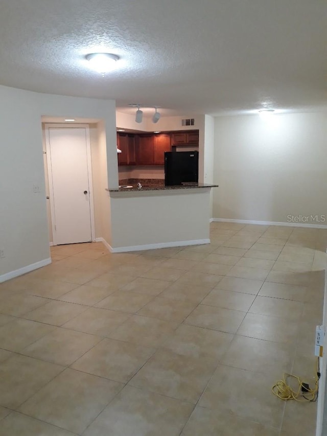 5725 Gatlin Ave Unit 315, Orlando, FL 32822 - kitchen featuring fridge, a textured ceiling, a peninsula, light tile patterned floors, and dark brown cabinets