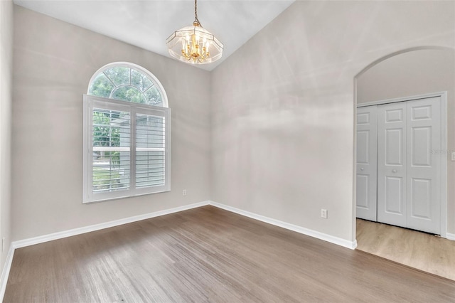 2675 Bond St, Clermont, FL 34711 - spare room with wood finished floors, a chandelier, arched walkways, and lofted ceiling