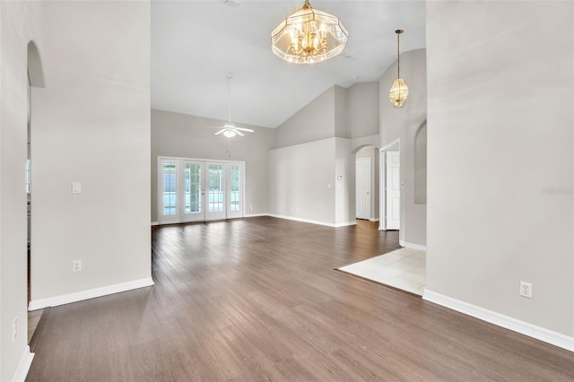 2675 Bond St, Clermont, FL 34711 - unfurnished living room with arched walkways, high vaulted ceiling, wood finished floors, a ceiling fan, and a chandelier