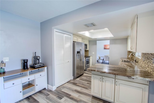 2005 Dalton Ave, Deltona, FL 32725 - kitchen featuring stainless steel appliances, light wood-style floors, a raised ceiling, decorative backsplash, and white cabinets