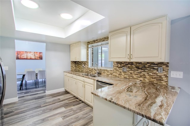 2005 Dalton Ave, Deltona, FL 32725 - kitchen featuring a tray ceiling, light wood-type flooring, a peninsula, light stone countertops, and tasteful backsplash