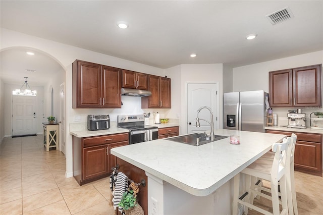 1010 Morvan Ln, Kissimmee, FL 34759 - kitchen with stainless steel appliances, under cabinet range hood, light countertops, a kitchen island with sink, and a breakfast bar area