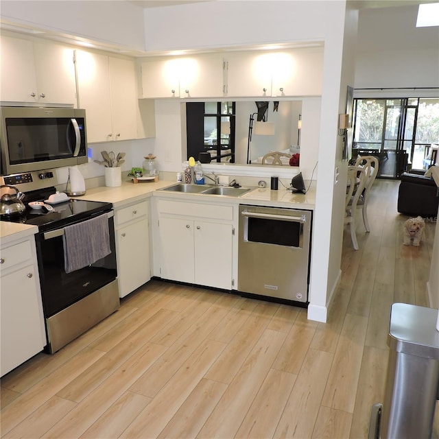 2480 Tahoe Cir Unit 2480, Winter Park, FL 32792 - kitchen with appliances with stainless steel finishes, light countertops, light wood finished floors, and white cabinetry