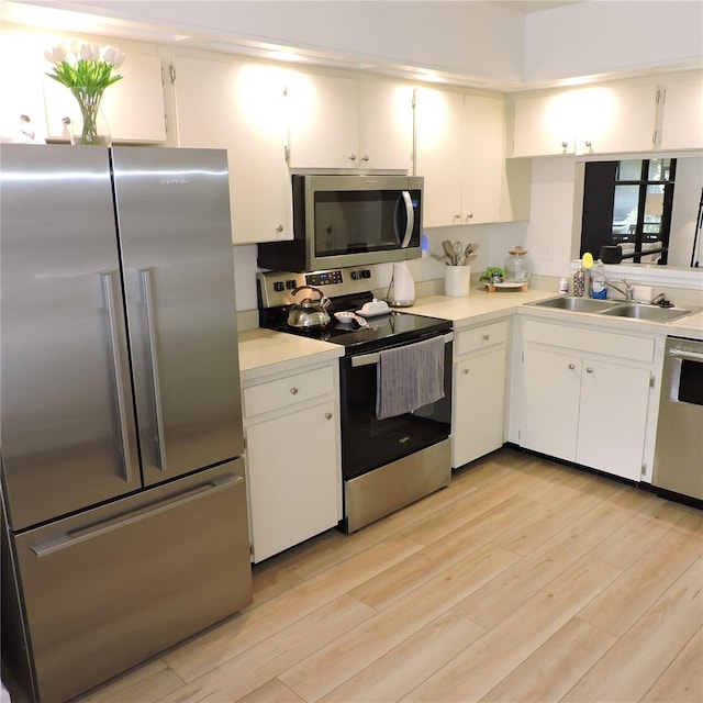 2480 Tahoe Cir Unit 2480, Winter Park, FL 32792 - kitchen featuring stainless steel appliances, light countertops, light wood finished floors, and white cabinets