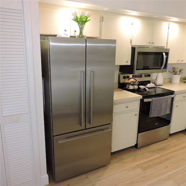 2480 Tahoe Cir Unit 2480, Winter Park, FL 32792 - kitchen featuring appliances with stainless steel finishes, light countertops, white cabinetry, and light wood finished floors