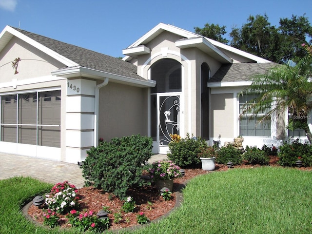 1430 Challenger Ave, Davenport, FL 33897 - ranch-style house with stucco siding, roof with shingles, an attached garage, a front yard, and decorative driveway