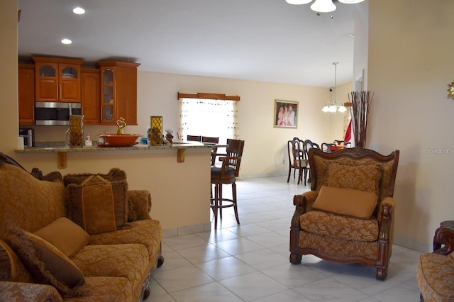 1436 Swan Ct, Kissimmee, FL 34759 - kitchen with stainless steel microwave, a kitchen bar, glass insert cabinets, brown cabinetry, and a peninsula
