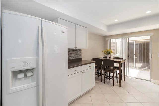 5057 Maui Cir Unit 15, Orlando, FL 32808 - kitchen with white refrigerator with ice dispenser, dark countertops, tasteful backsplash, white cabinetry, and light tile patterned floors