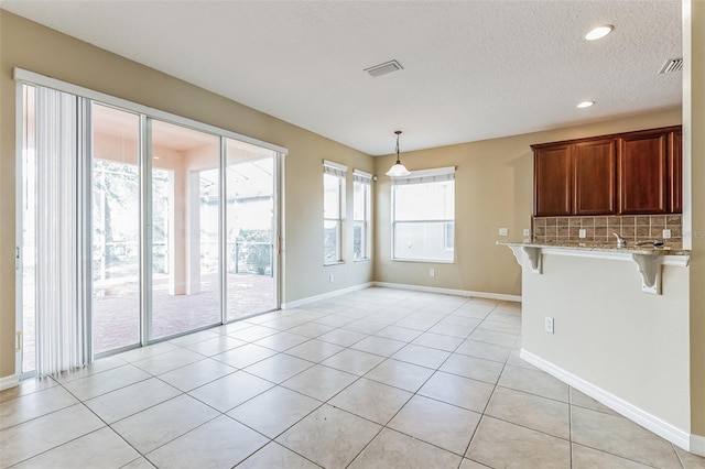 7184 Maleberry Run, Winter Garden, FL 34787 - kitchen featuring a kitchen breakfast bar, decorative backsplash, light stone countertops, light tile patterned floors, and hanging light fixtures