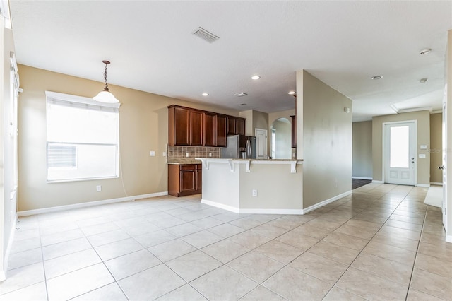 7184 Maleberry Run, Winter Garden, FL 34787 - kitchen featuring stainless steel fridge with ice dispenser, decorative backsplash, a kitchen breakfast bar, light countertops, and a peninsula