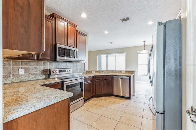 7184 Maleberry Run, Winter Garden, FL 34787 - kitchen featuring appliances with stainless steel finishes, a peninsula, light tile patterned floors, decorative backsplash, and light stone counters