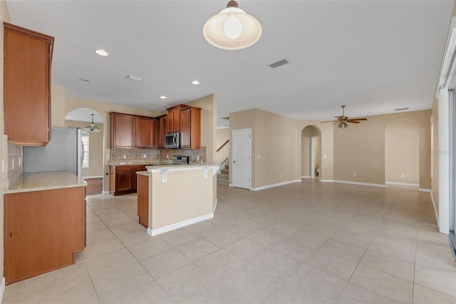 7184 Maleberry Run, Winter Garden, FL 34787 - kitchen featuring stainless steel appliances, arched walkways, backsplash, open floor plan, and light countertops
