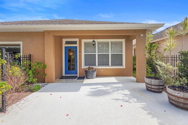 12868 Holdenbury Ln, Windermere, FL 34786 - view of exterior entry featuring stucco siding, a patio area, and roof with shingles