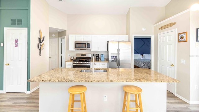 131 Sonja Cir, Davenport, FL 33897 - kitchen featuring appliances with stainless steel finishes, high vaulted ceiling, a kitchen bar, and light wood-style flooring
