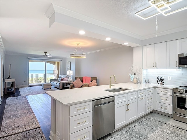 60 Surfview Dr Unit 308, Palm Coast, FL 32137 - kitchen featuring appliances with stainless steel finishes, a peninsula, ornamental molding, white cabinetry, and decorative backsplash