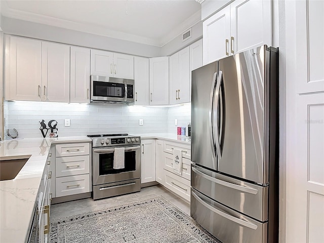 60 Surfview Dr Unit 308, Palm Coast, FL 32137 - kitchen with appliances with stainless steel finishes, backsplash, white cabinetry, crown molding, and light stone counters