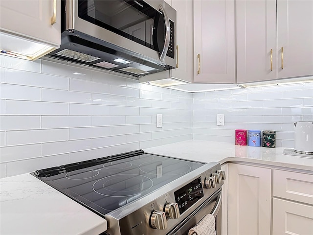 60 Surfview Dr Unit 308, Palm Coast, FL 32137 - kitchen featuring stainless steel appliances, decorative backsplash, white cabinets, and light stone countertops
