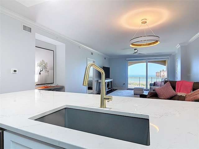 60 Surfview Dr Unit 308, Palm Coast, FL 32137 - kitchen featuring open floor plan, crown molding, light stone counters, hanging light fixtures, and carpet flooring