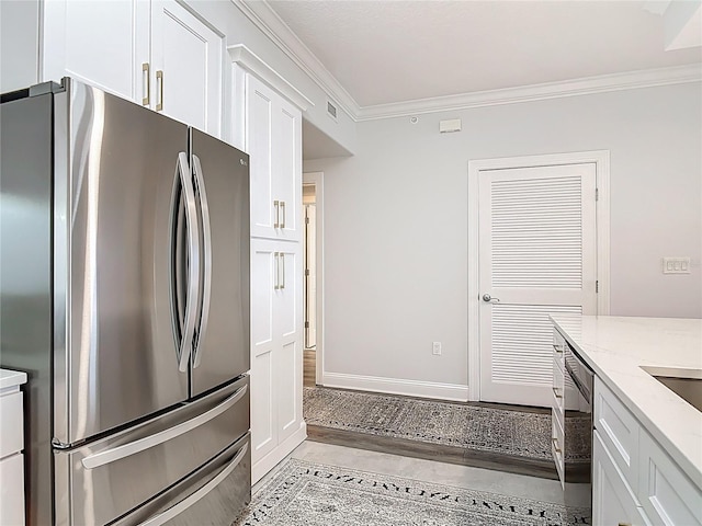 60 Surfview Dr Unit 308, Palm Coast, FL 32137 - kitchen with freestanding refrigerator, ornamental molding, white cabinets, and light stone counters