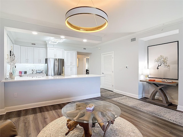60 Surfview Dr Unit 308, Palm Coast, FL 32137 - kitchen featuring appliances with stainless steel finishes, crown molding, dark wood-style floors, white cabinets, and decorative backsplash