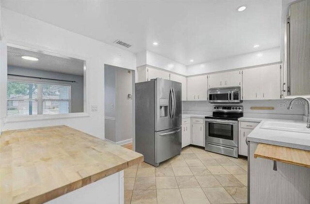 2813 21st Ave W, Bradenton, FL 34205 - kitchen featuring stainless steel appliances, wooden counters, light tile patterned floors, white cabinets, and recessed lighting