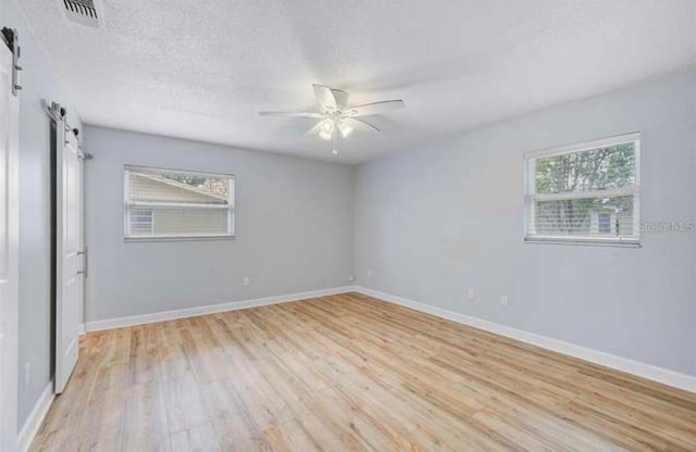 2813 21st Ave W, Bradenton, FL 34205 - spare room featuring a barn door, light wood-type flooring, and a ceiling fan