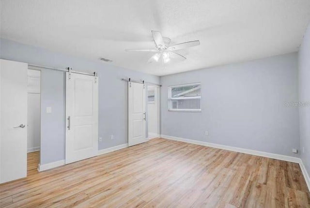 2813 21st Ave W, Bradenton, FL 34205 - unfurnished bedroom featuring a barn door, wood finished floors, and ceiling fan