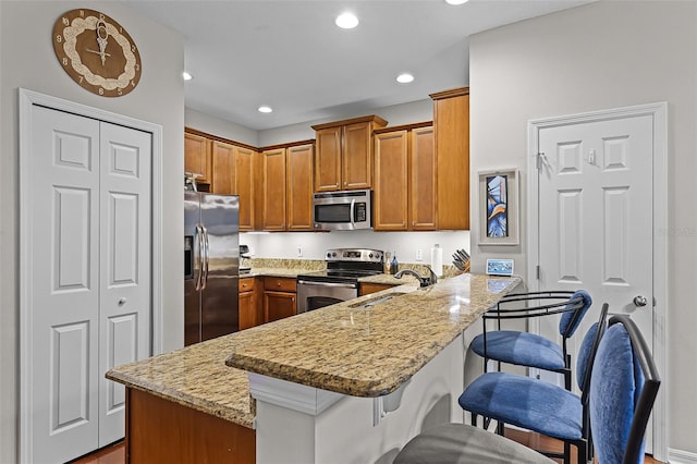 14242 Desert Haven St Unit Ge, Windermere, FL 34786 - kitchen with stainless steel appliances, a peninsula, brown cabinets, a breakfast bar, and light stone counters