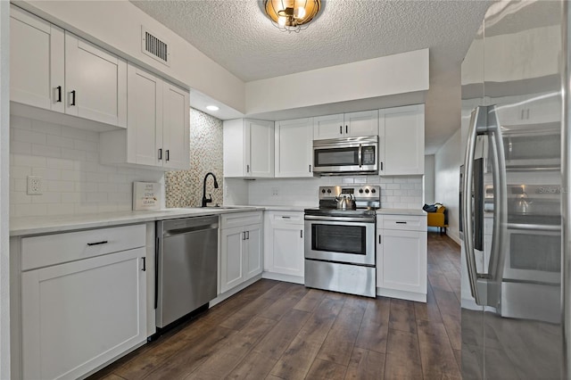 2257 World Parkway Blvd W Unit 61, Clearwater, FL 33763 - kitchen with stainless steel appliances, dark wood finished floors, white cabinetry, a textured ceiling, and light countertops