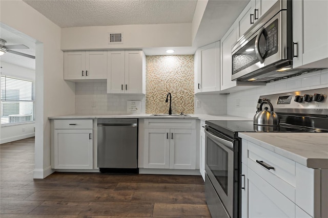 2257 World Parkway Blvd W Unit 61, Clearwater, FL 33763 - kitchen featuring stainless steel appliances, dark wood-style floors, white cabinetry, a ceiling fan, and decorative backsplash
