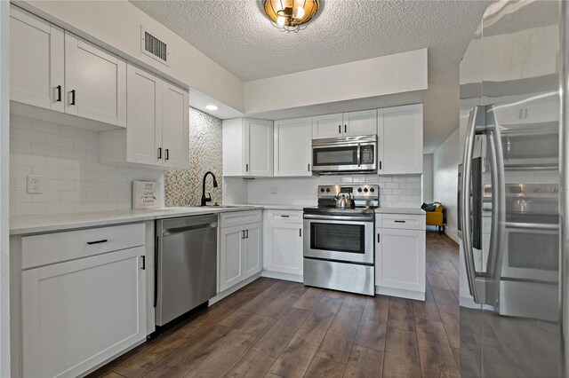2257 World Parkway Blvd W Unit 61, Clearwater, FL 33763 - kitchen with stainless steel appliances, dark wood-style floors, white cabinets, a textured ceiling, and light countertops