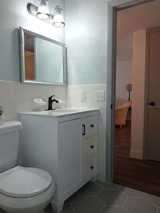 2257 World Parkway Blvd W Unit 61, Clearwater, FL 33763 - half bath featuring tile walls, tile patterned flooring, vanity, wainscoting, and a textured wall