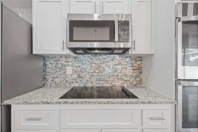 17032 Winners Cir, Odessa, FL 33556 - kitchen with stainless steel appliances, white cabinetry, decorative backsplash, and light stone counters