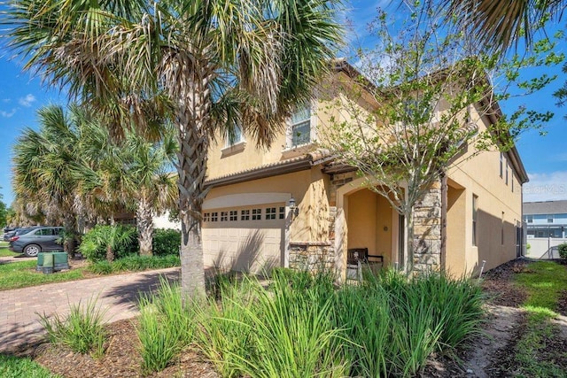 8901 Rhodes St, Kissimmee, FL 34747 - mediterranean / spanish-style house with stucco siding, an attached garage, driveway, and stone siding