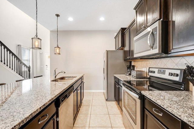 8901 Rhodes St, Kissimmee, FL 34747 - kitchen with appliances with stainless steel finishes, tasteful backsplash, decorative light fixtures, dark brown cabinetry, and light stone countertops