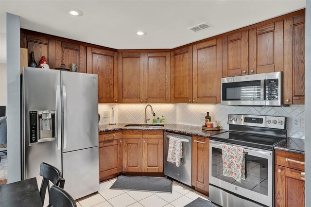 1165 Indian Ridge Trl E, Kissimmee, FL 34747 - kitchen featuring appliances with stainless steel finishes, backsplash, brown cabinets, dark stone counters, and recessed lighting