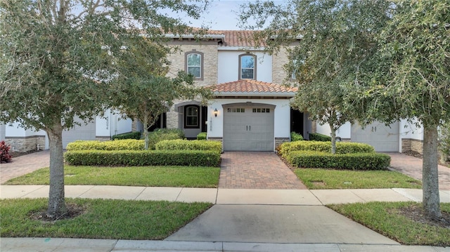 14088 Tarvin St, Orlando, FL 32832 - mediterranean / spanish house featuring a tile roof, decorative driveway, stone siding, and stucco siding